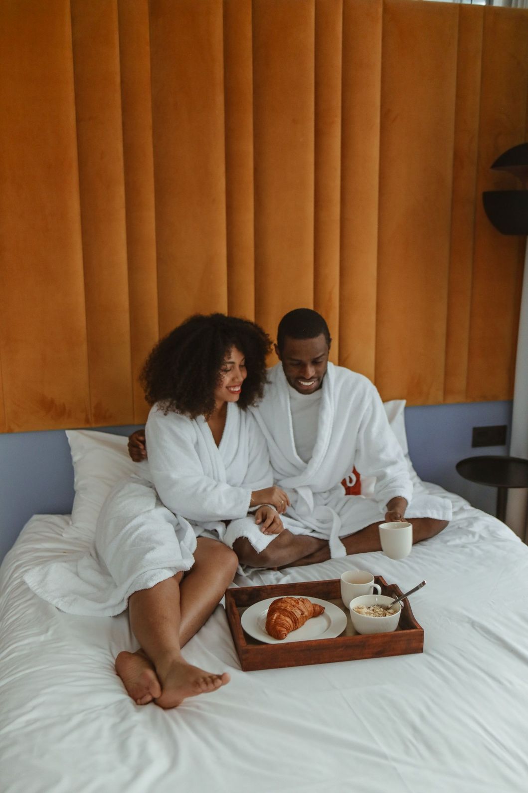 Couple eating breakfast on a hotel bed